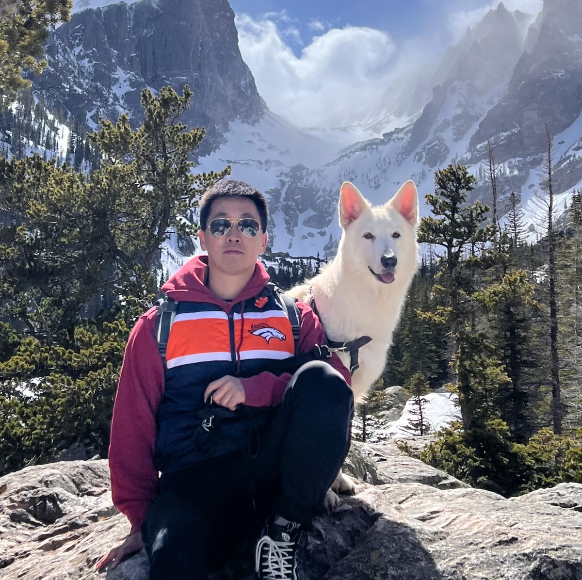 Yawen Shen with a white dog in front of snowy mountains